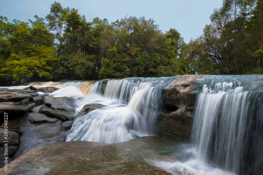 Fototapeta premium Waterfalls in tropical forests, Water from the creek flows onto the rocks, Cause a beautiful waterfall.