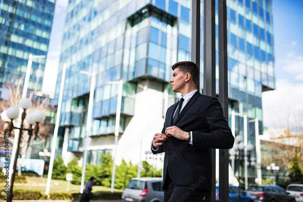 Young smart businessman in suit standing against financial district Young smart businessman in suit standing against financial district