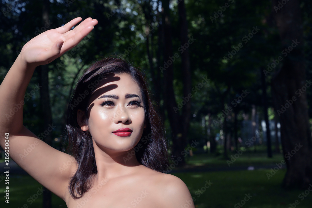 Beautiful woman hold up her hand to protect heat from the sun Beautiful woman hold up her hand to protect heat from the sun