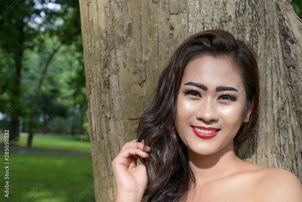 Asian young woman happy smile in front of the big tree in the park Asian young woman happy smile in front of the big tree in the park