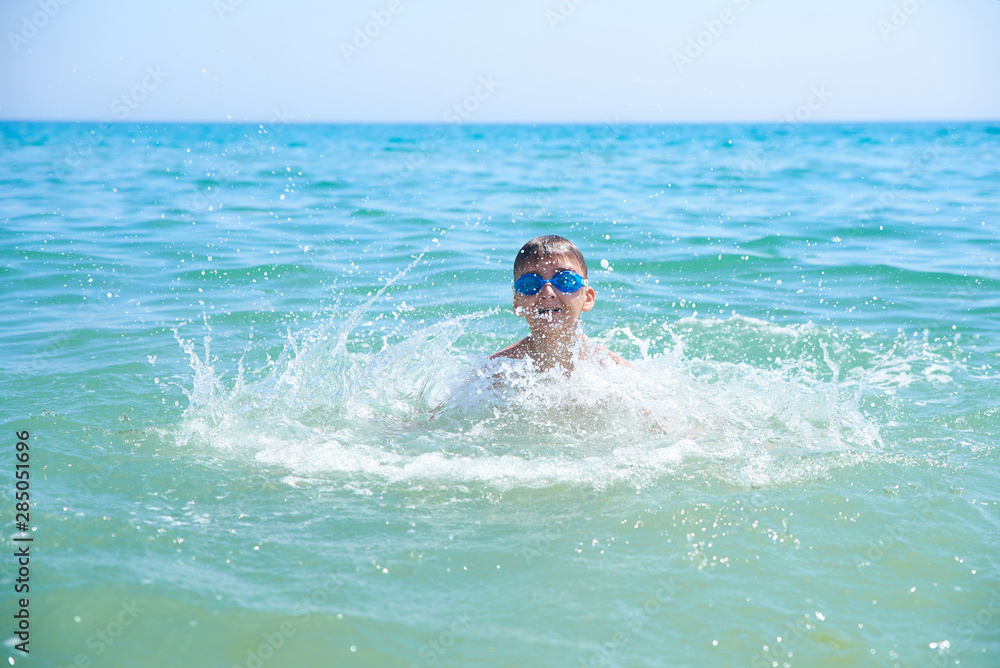 BOY TEENAGERS IN WATER GOGGLES SWIM IN THE SEA