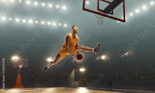 Basketball player scoring a slam dunk basket. Floodlit basketball court
