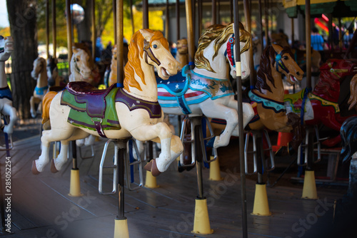 Beautiful Colorful old carousel in a holiday park. Merry go round with vintage wooden horses during fall or autumn season.