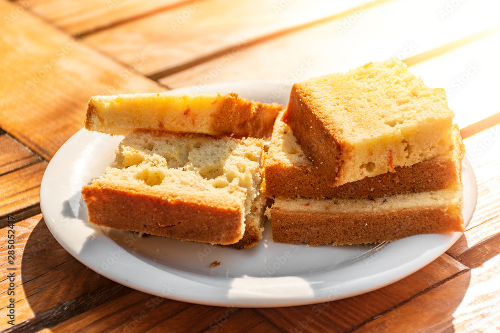 pieces of cake on a plate on a wooden table in the sun pieces of cake on a plate on a wooden table in the sun