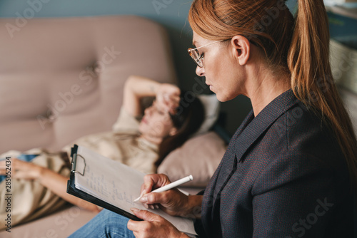 Photo of thoughtful caucasian woman having conversation with psychologist in room