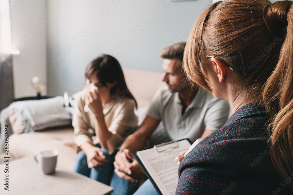 Photo of caucasian unhappy couple having conversation with psychologist on therapy session in room Photo of caucasian unhappy couple having conversation with psychologist on therapy session in room