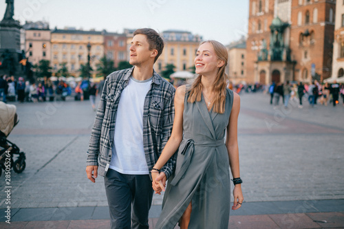 Happy loving couple smiling and walking throug the main square in Krakow (Cracow)