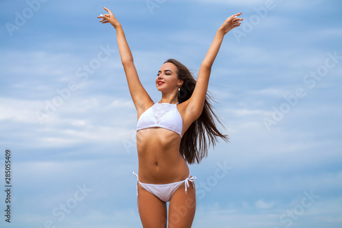 Sexy woman in white bikini on blue sky background