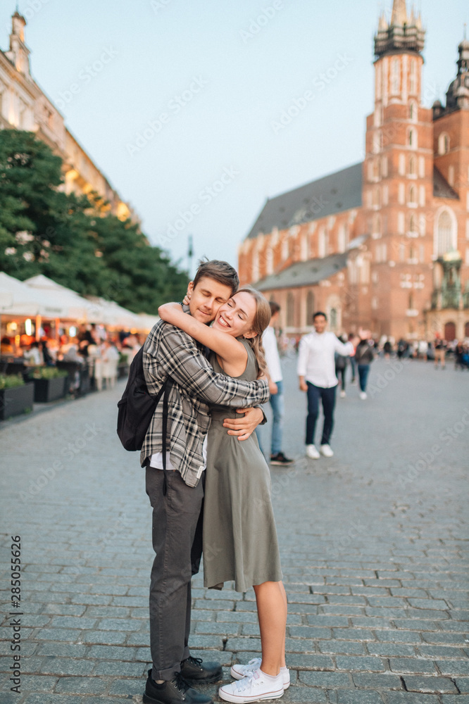 Young loving couple hugs at central square in Krakow (Cracow).