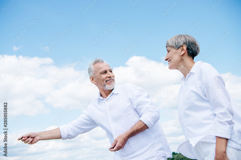 happy smiling senior couple in white shirts looking at each other under blue sky happy smiling senior couple in white shirts looking at each other under blue sky