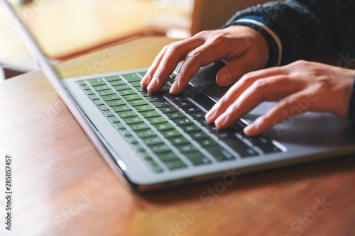 Closeup image of hands using and typing on laptop computer keyboard on the table