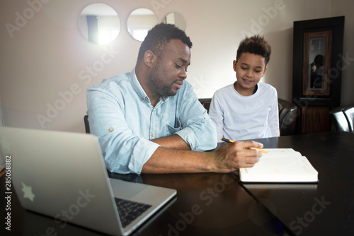 Mixed family at home. African father and african american child. dad helping son with school homework. Education and relationship, man teaching and boy learning. home schooling.