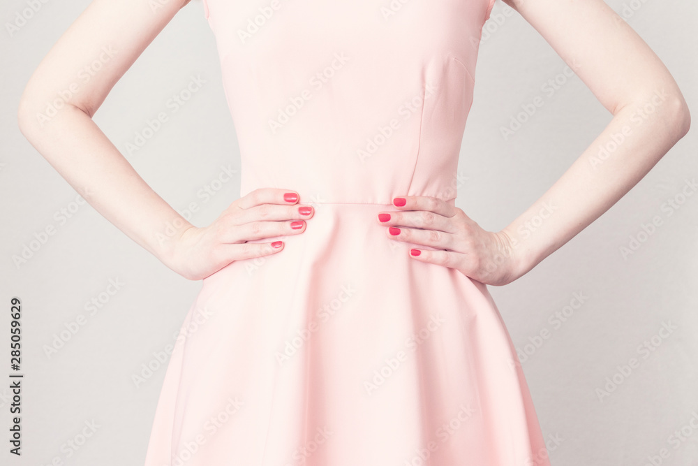 Woman's hands at the waist, close-up. The woman in the pink dress to be angry with someone, keeps hands on waist, cropped image, toned Woman's hands at the waist, close-up. The woman in the pink dress to be angry with someone, keeps hands on waist, cropped image, toned