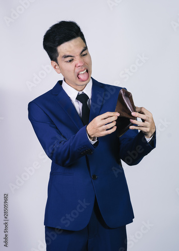 Portrait handsome young asian .businessman wearing a blue suit stressed because empty wallet no money isolated on grey background in studio. Asian man people. business success concept.