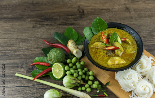 Green curry (Kaeng kheiyw hwan) with Thai food for steamed rice or rice noodles. chicken green curry is thai food very popular on dark wooden background. top view