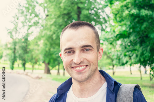 Portrait, young attractive traveler smiling, man stands on the road, looking in the camera, close up, toned