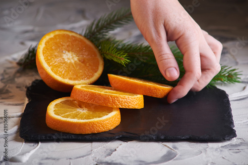 Photos Fresh slised oranges and spruce branch on the gray background