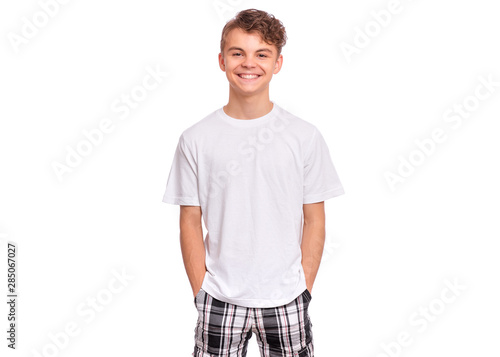 T-shirt design concept. Teen boy in blank white t-shirt, isolated on white background. Mock up template for print. Happy child with hands in pockets looking at camera, front view.