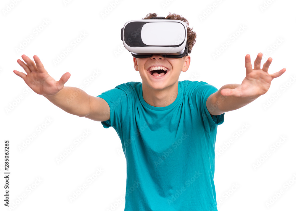 Fototapeta premium Happy teen boy wearing virtual reality goggles watching movies or playing video games. Cheerful smiling teenager looking in VR glasses. Funny child experiencing 3D gadget technology.