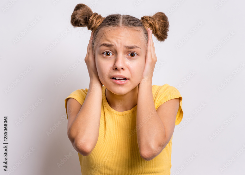 Tight cropped face of a scared young girl with hands covering