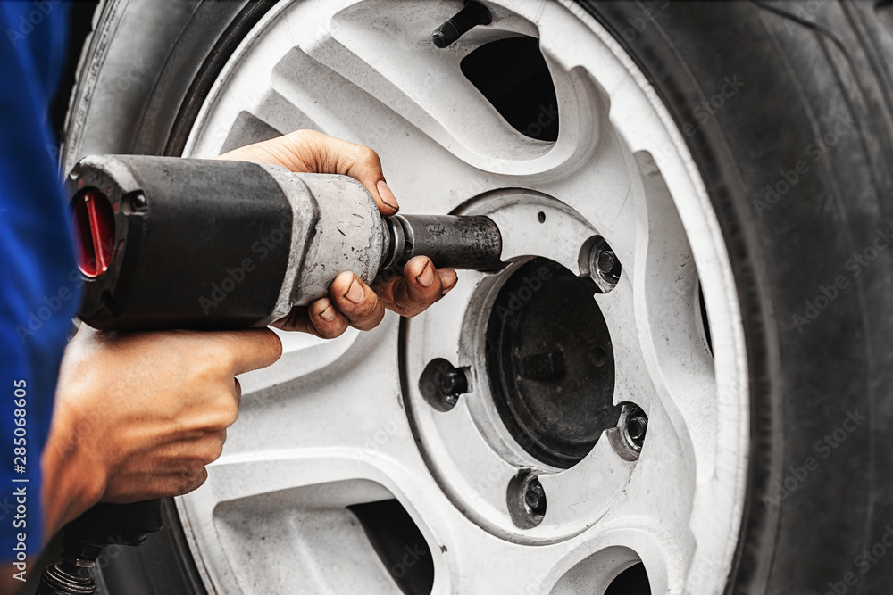 close up auto mechanic changing car wheel with tool machine close up auto mechanic changing car wheel with tool machine