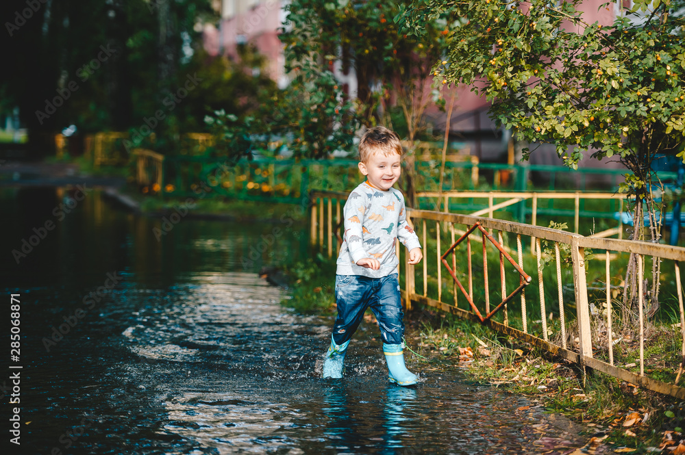 Cute child walking on puddle after a rain