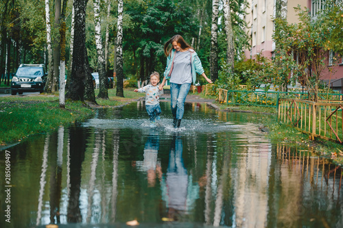 Obraz na płótnie Young mother with little son walking in the street after a rain. w salonie
