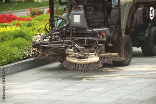 Картината върху платно A street sweeper sweeps up a stone pavement with a strong brush in rainy weather
