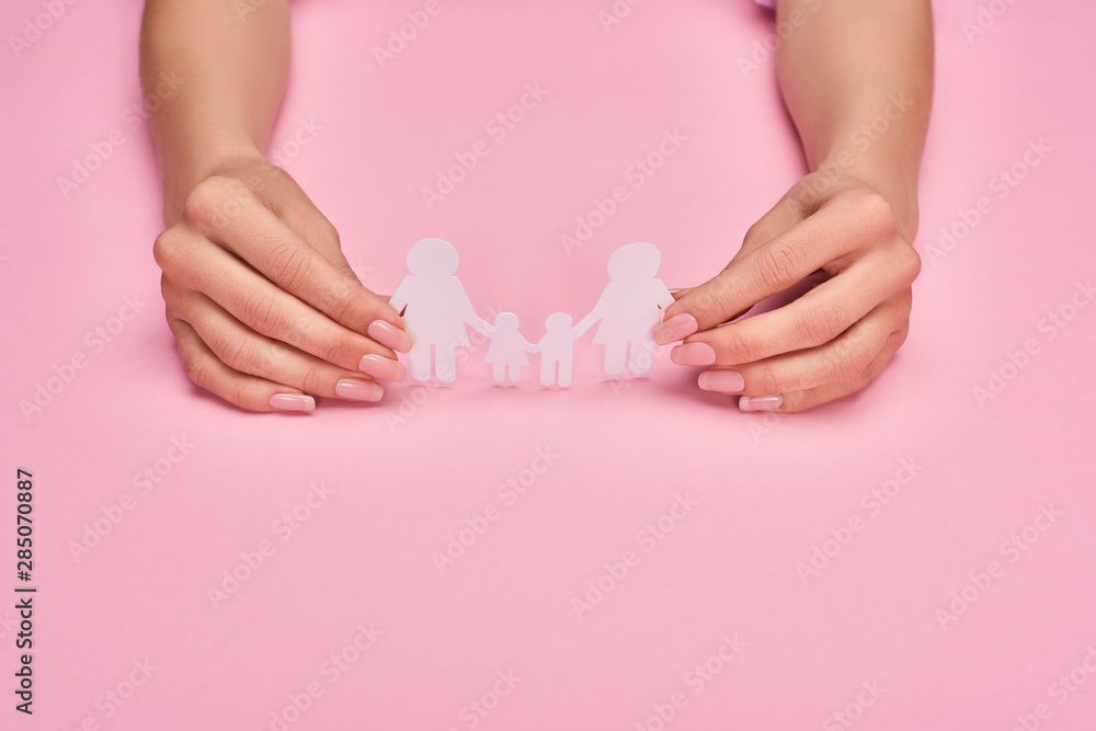 cropped view of woman holding paper cut lesbian family on pink background cropped view of woman holding paper cut lesbian family on pink background