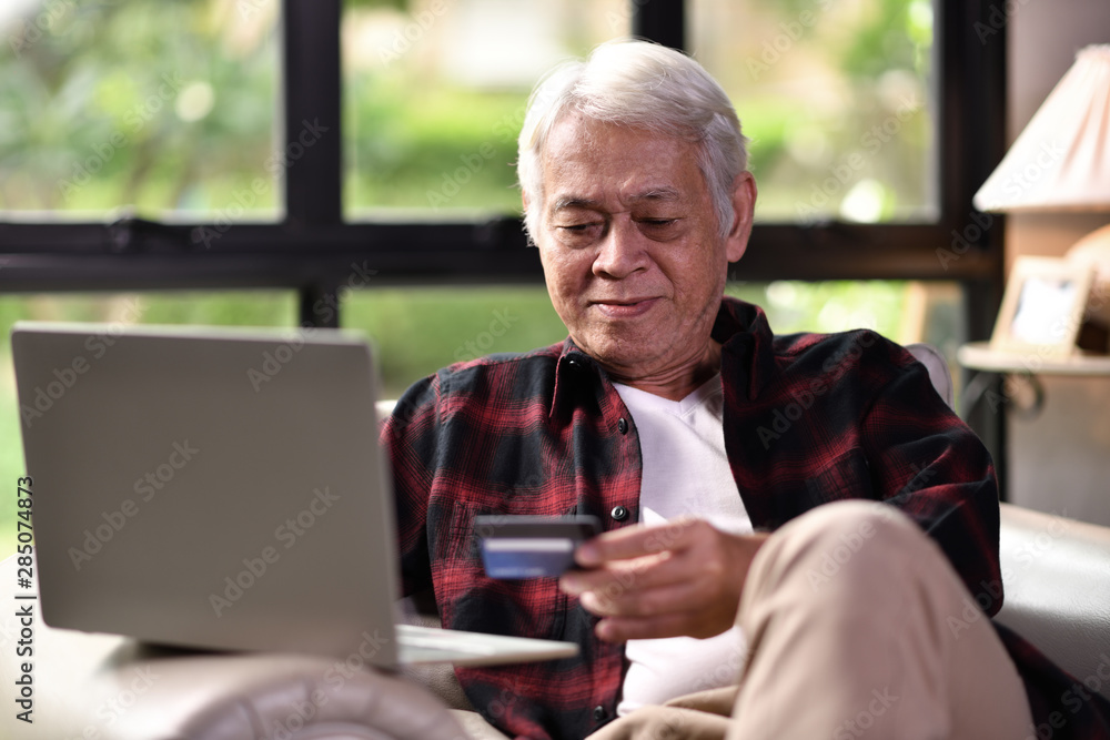 Happy Asian senior man using credit card for online shopping Happy Asian senior man using credit card for online shopping
