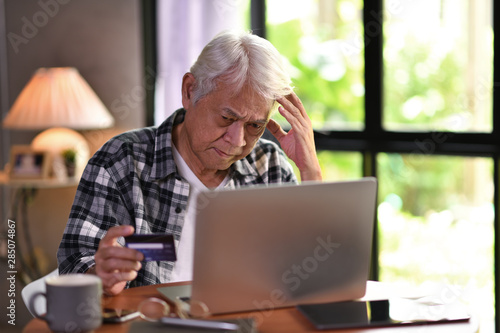 Photography Asian senior man looking confuse when using credit card for online shopping