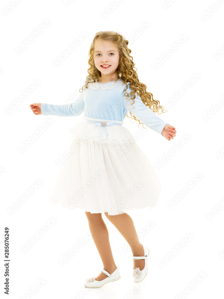 A little girl in a dress is spinning.