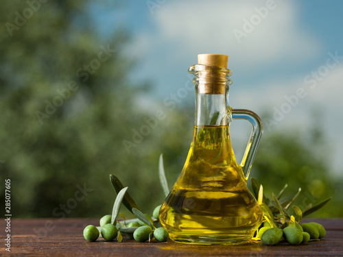 Fototapeta Olive oil bottle on wooden table, natural oils concept