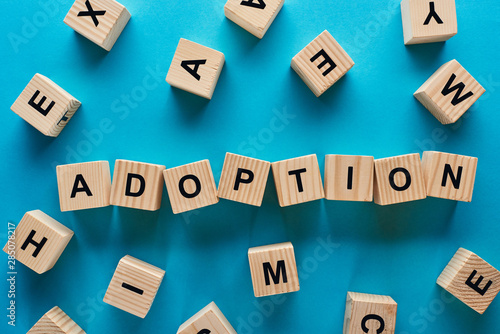 top view of adoption word made of wooden cubes on blue background photo