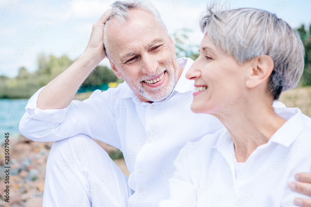 happy smiling senior couple in white shirts embracing under blue sky happy smiling senior couple in white shirts embracing under blue sky