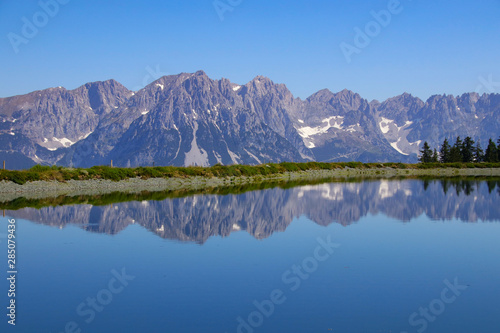 Hiking trail around a small lake at Kaiser mountains (Scheffau, Wilder kaiser) and beautiful reflections in water, Tyrol - Austria