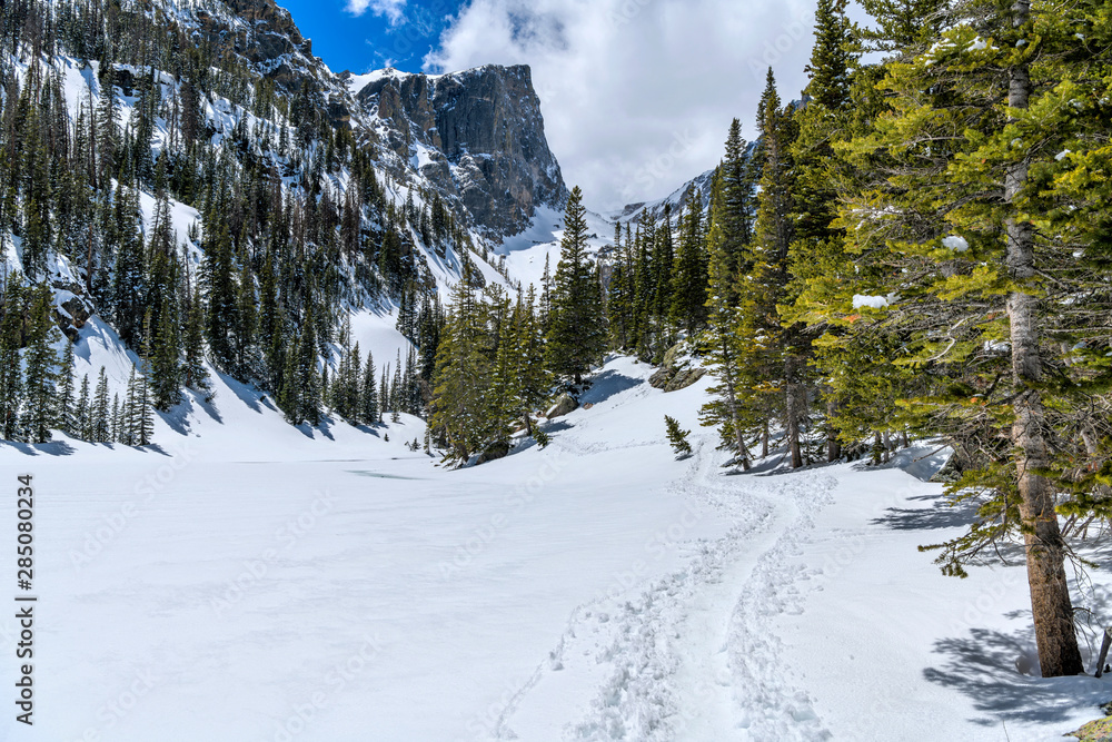 Snow Trail - A snow hiking trail winding along side of froze Dream Lake towards towering Hallett Peak. Rocky Mountain National Park, Colorado, USA.