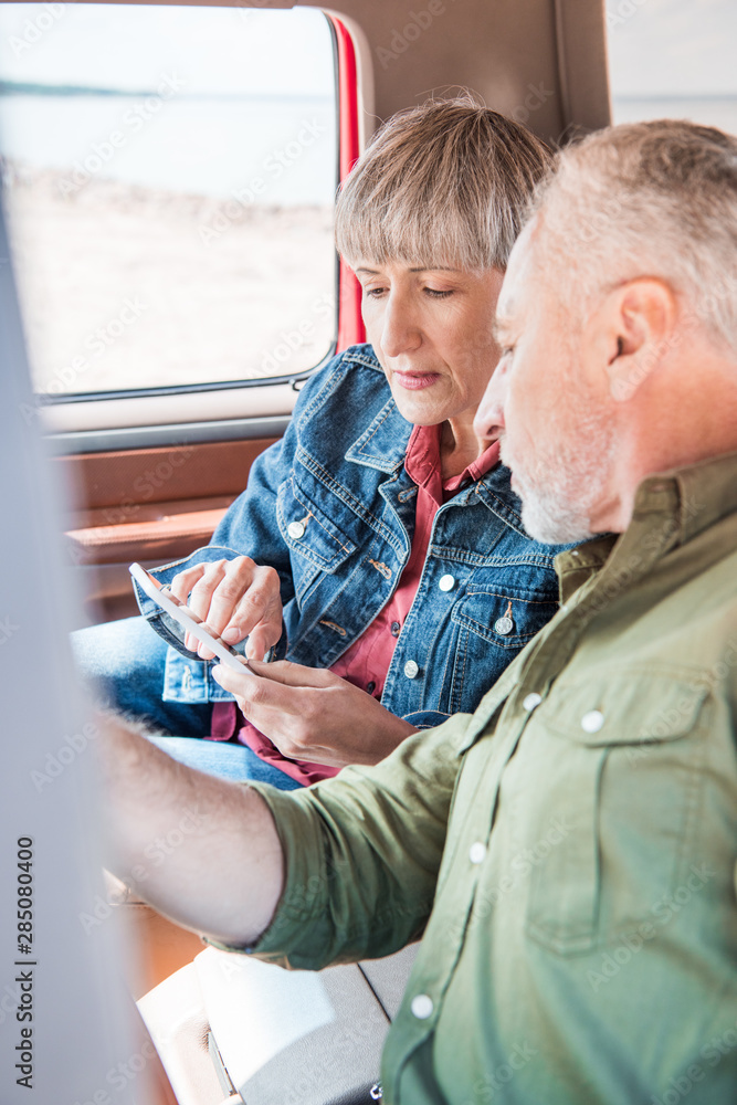senior couple using smartphone in car in sunny day senior couple using smartphone in car in sunny day