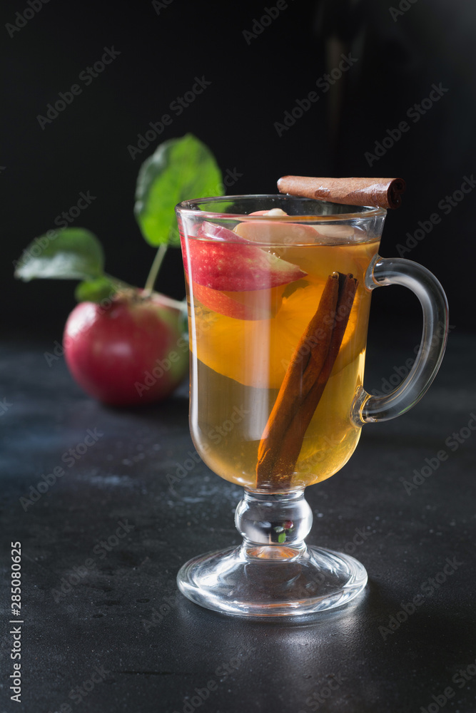 Glass of warm apple tea with lemon and cinnamon on black board. Autumn still life. Glass of warm apple tea with lemon and cinnamon on black board. Autumn still life.