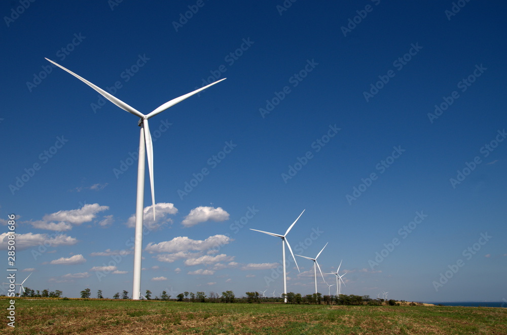Wind farms built along the road against the background of the sea and cloudy sky Wind farms built along the road against the background of the sea and cloudy sky