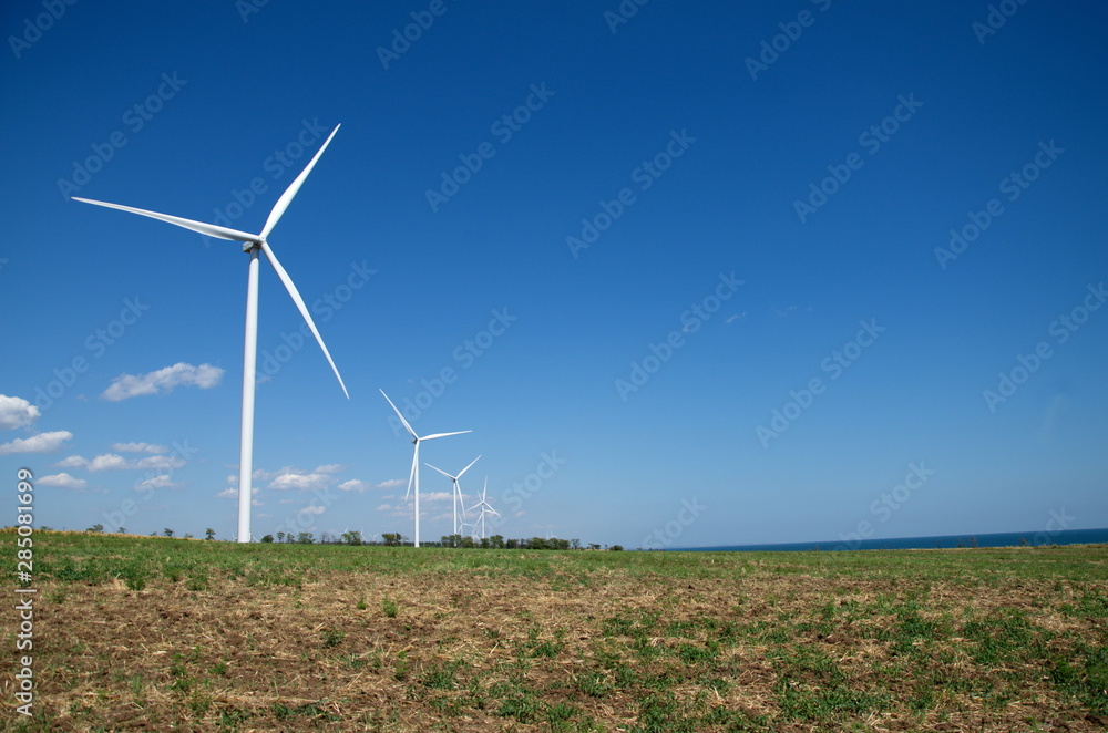 Wind power stations on the background of the steppe and the sea Wind power stations on the background of the steppe and the sea