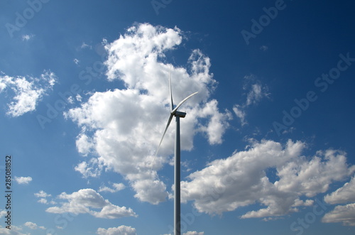 Full size wind farm against a blue sky in the middle of a field