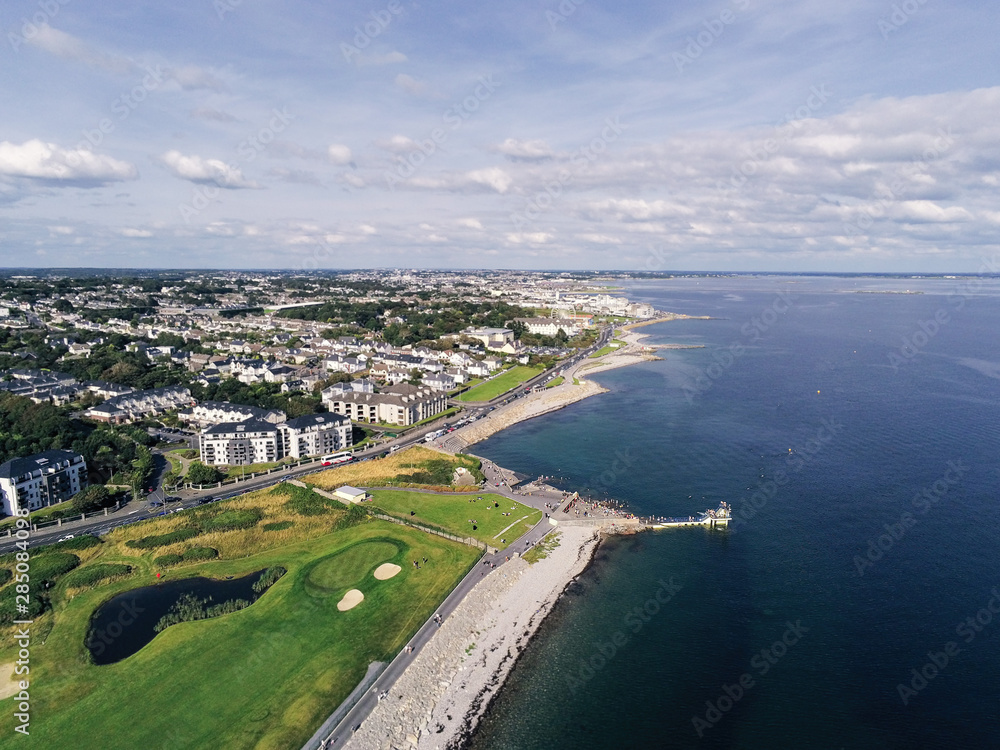 Aerial view on Salthill, Galway city, Ireland, Tilt shift effect, Blackrock diving board, Warm sunny day. People swimming in the ocean.