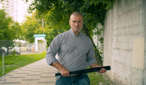 An angry bully with a bat in his hands