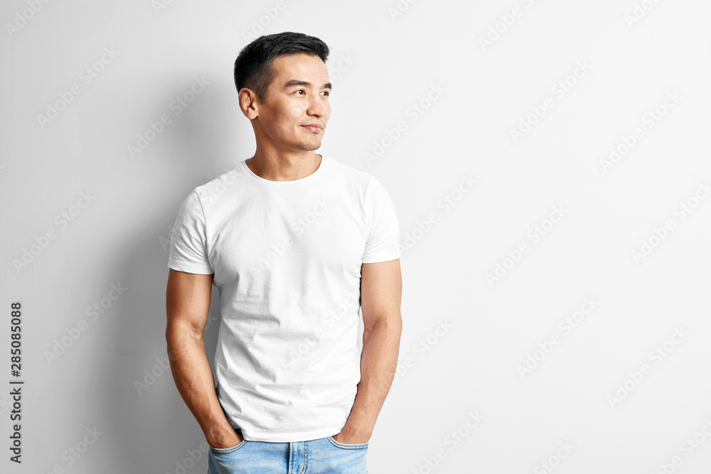 Portrait of young asian designer dressed in casual against white wall. Handsome Kazakh man joyfully smiles in studio Portrait of young asian designer dressed in casual against white wall. Handsome Kazakh man joyfully smiles in studio