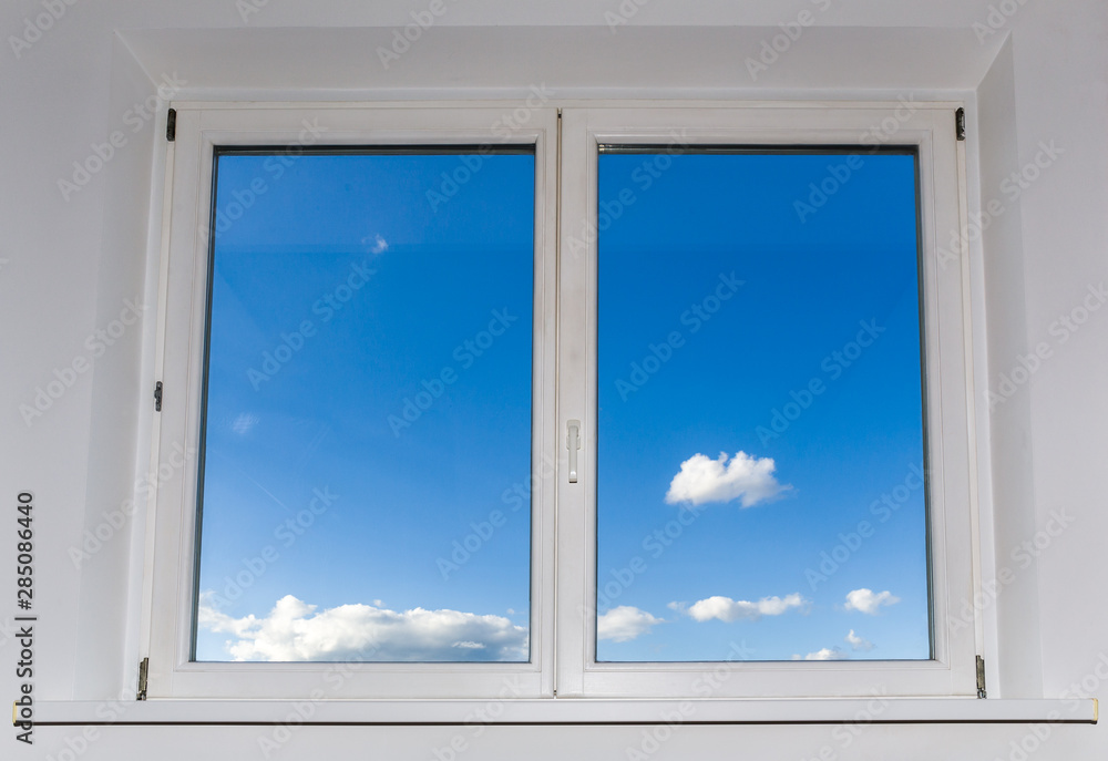 View of closed white window overlooking blue sky with clouds, view from home View of closed white window overlooking blue sky with clouds, view from home