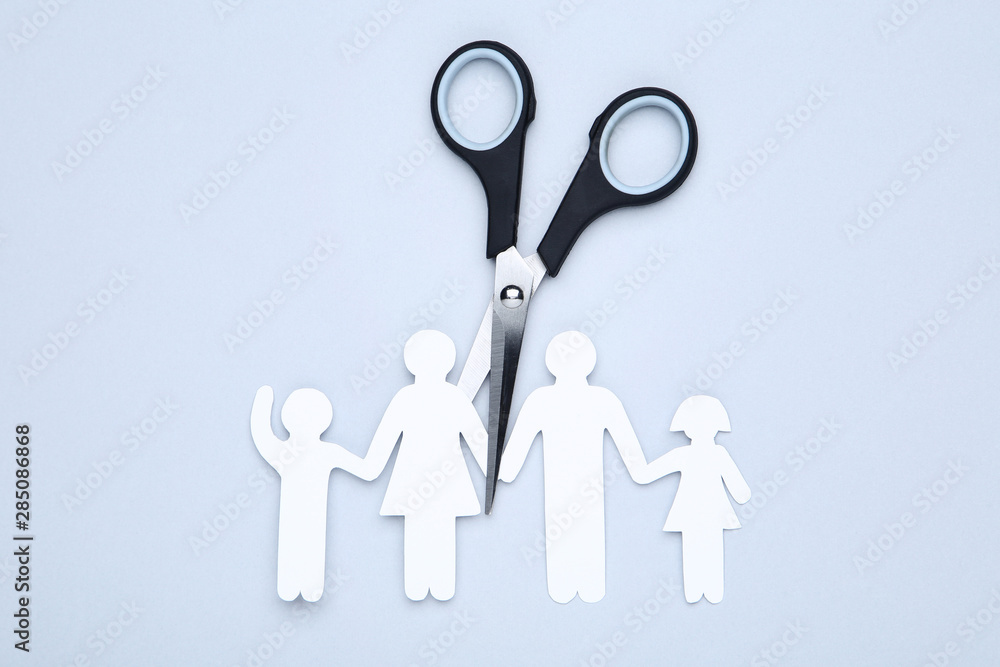 Family figures with scissors on grey background Family figures with scissors on grey background