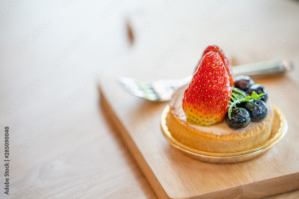 a small round tart of strawberry cheese cake with blueberry and mint