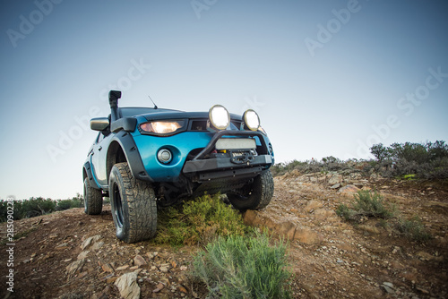 Close up wide angle image of a modified 4x4 pick up truck driving on a 4x4 track in nature. © Dewald
