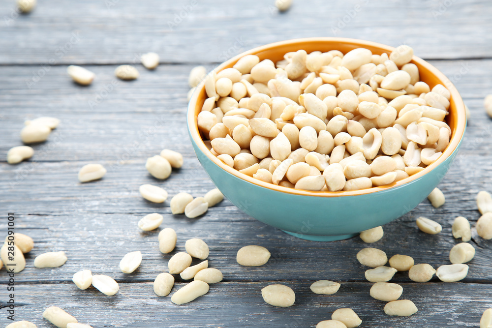 Peanuts in bowl on grey wooden table Peanuts in bowl on grey wooden table